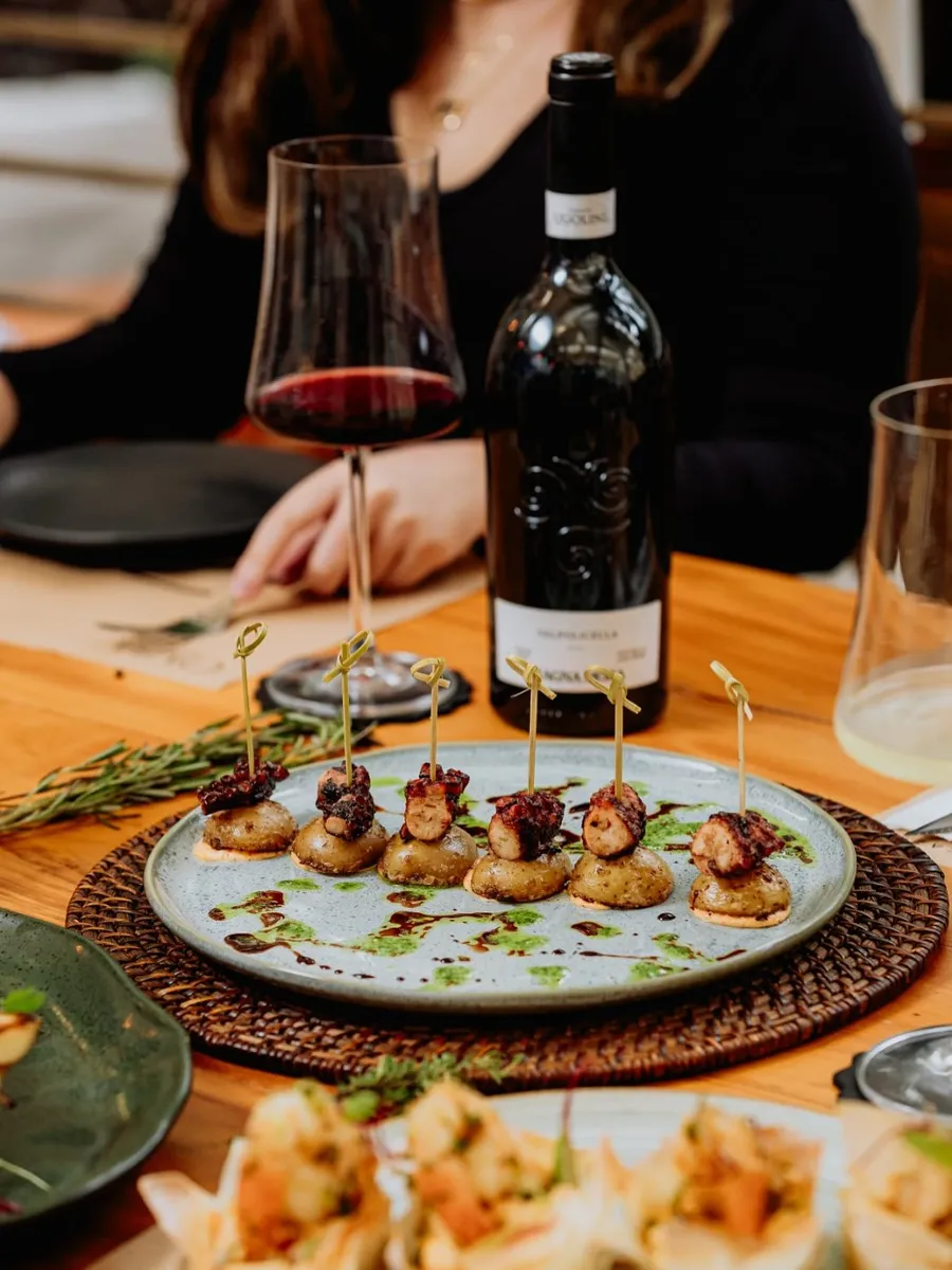 Pratos autorais e vinho na mesa da Caza Raro