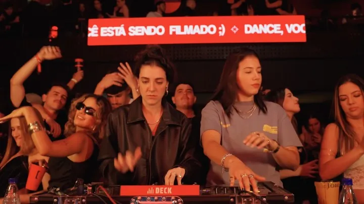 DJ set do Boiler Deck: DJs na cabine, público em volta e o letreiro “Dance, você está sendo filmado”
