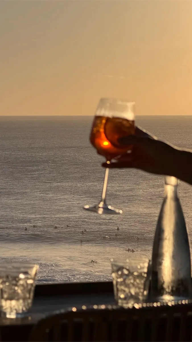 Taça contra o pôr do sol, com kitesurfistas no mar